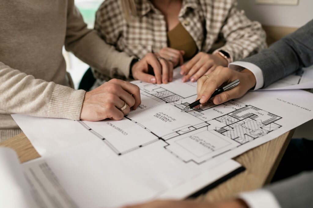 pexels-photo-7641859-7641859 Group examining house floor plans with a real estate agent, highlighting home buying process.